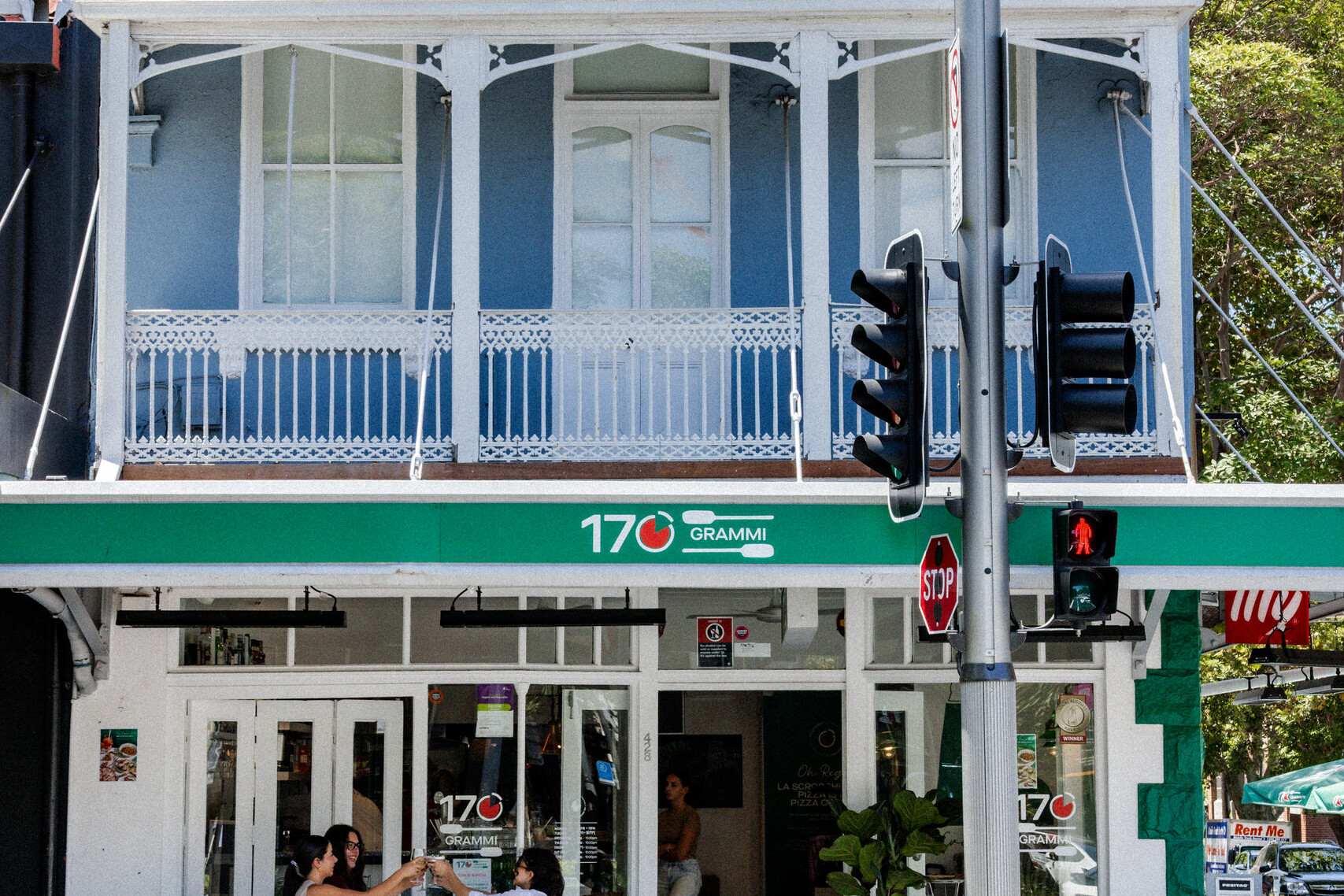 Exterior of 170 Grammi in Surry Hills, a blue heritage-style building with green signage and outdoor seating on a sunny street corner.