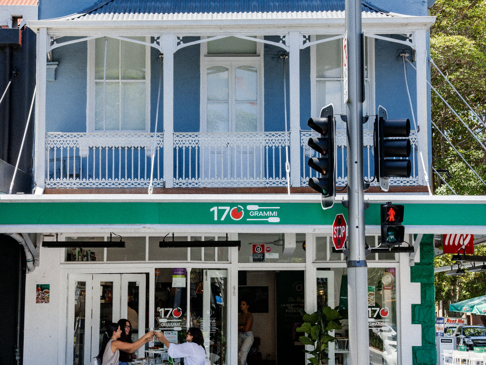 Exterior of 170 Grammi in Surry Hills, a blue heritage-style building with green signage and outdoor seating on a sunny street corner.