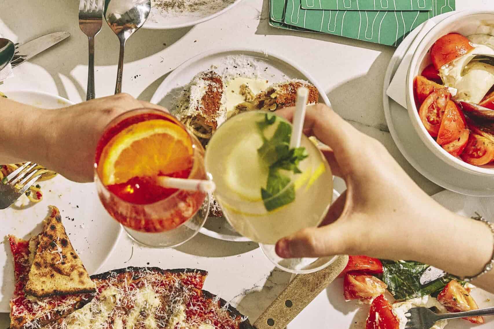 Top view of a vibrant Italian feast featuring wood-fired pizzas, burrata, olives, mortadella, and antipasti at 170 Grammi in Sydney