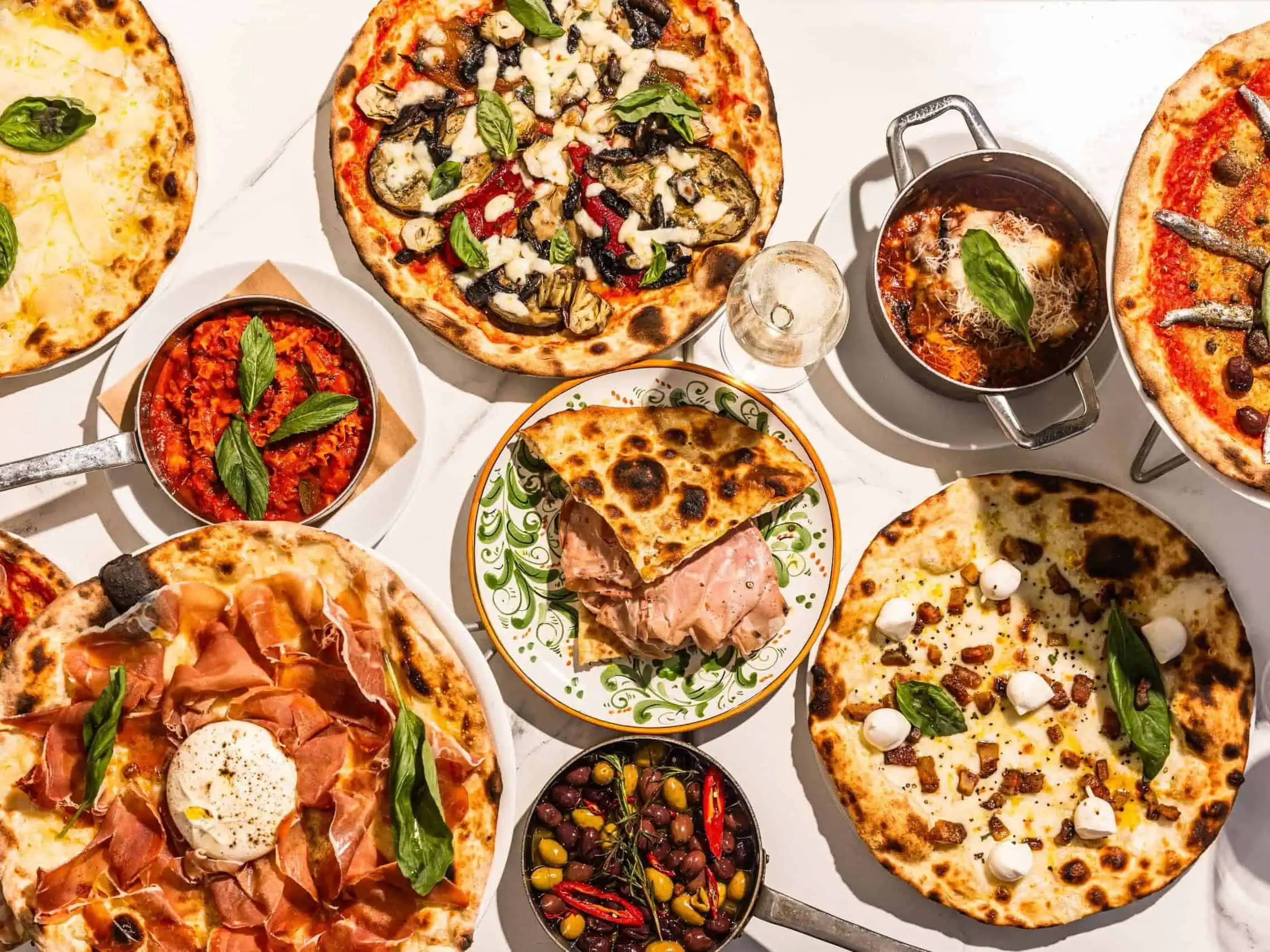 Top view of a vibrant Italian feast featuring wood-fired pizzas, burrata, olives, mortadella, and antipasti at 170 Grammi in Sydney