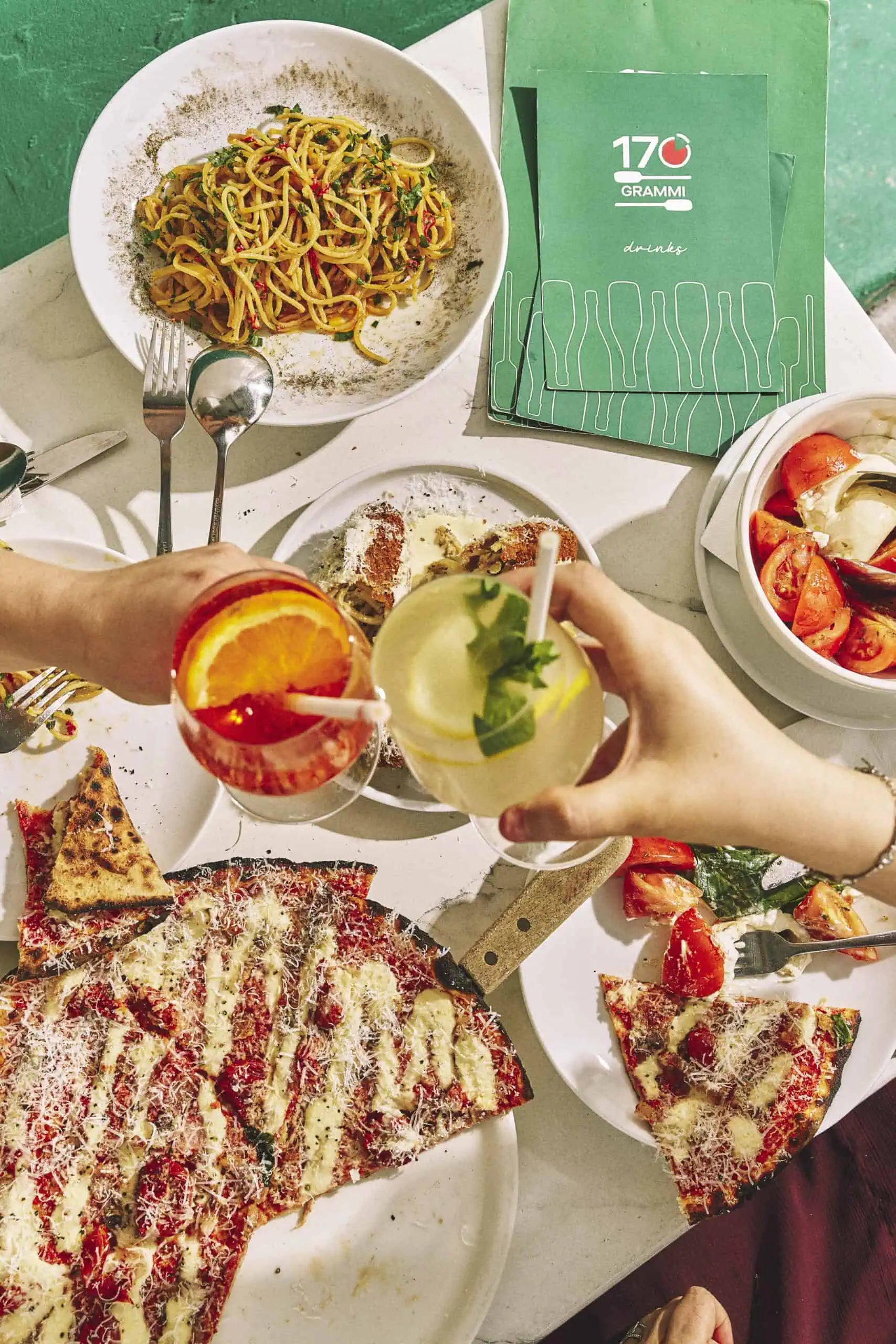 Top view of a vibrant Italian feast featuring wood-fired pizzas, burrata, olives, mortadella, and antipasti at 170 Grammi in Sydney