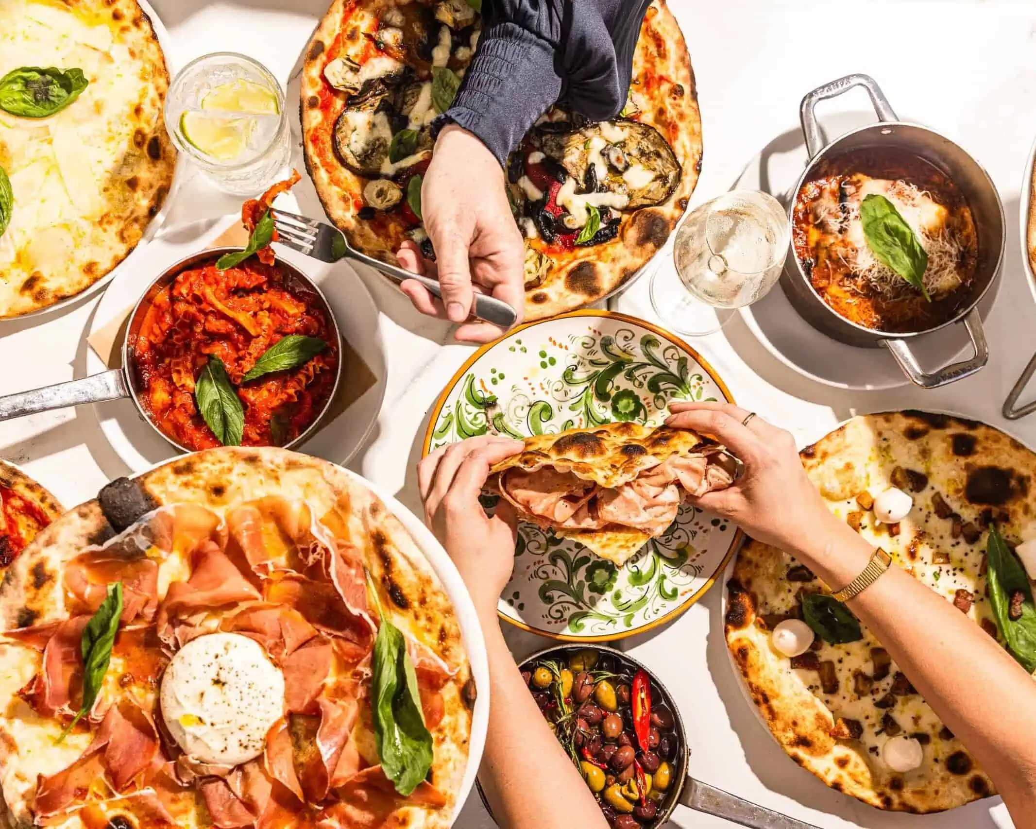 Overhead view of diners sharing Italian pizzas, antipasti, and schiacciata with mortadella at 170 Grammi in Sydney
