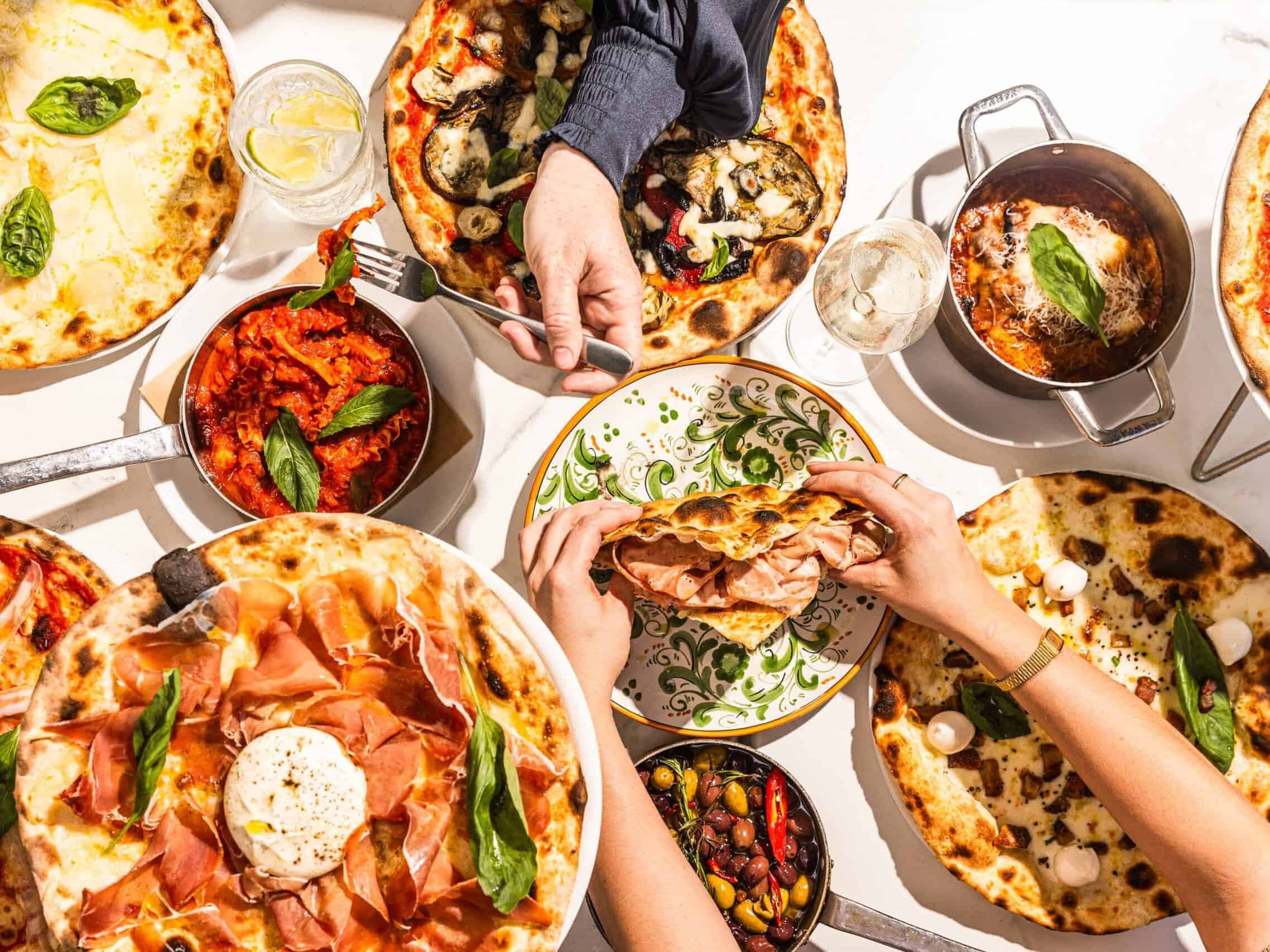 Overhead view of diners sharing Italian pizzas, antipasti, and schiacciata with mortadella at 170 Grammi in Sydney