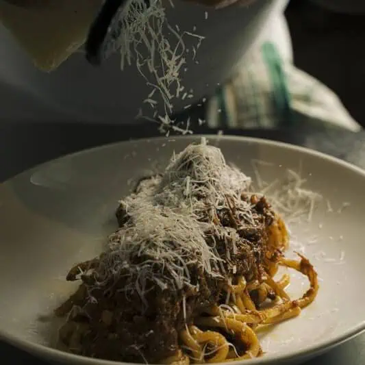 Traditional Roman bucatini alla vaccinara served with rich oxtail ragù, toasted pinenuts, and a hint of dark chocolate