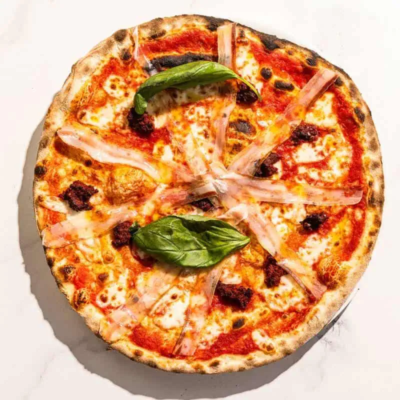 Spicy Calabrese pizza with San Marzano tomato, buffalo mozzarella, ’nduja, pancetta, fresh basil, and Coratina EVOO