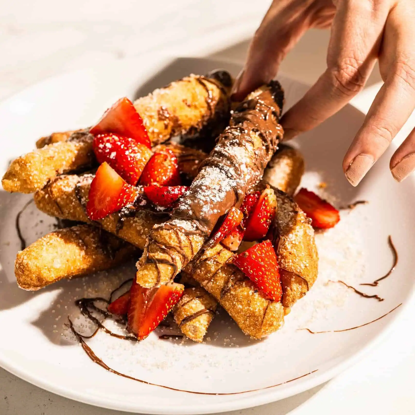 Lightly fried Italian dough sticks drizzled with Nutella and topped with fresh strawberries, a sweet and indulgent treat