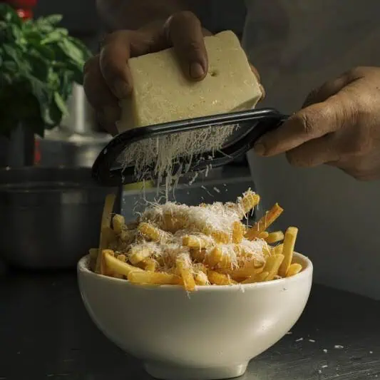Crispy fries topped with grated Pecorino Romano cheese and cracked black pepper, Italian-inspired side dish
