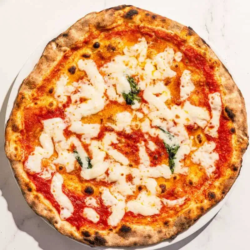 Classic Margherita pizza topped with San Marzano tomatoes, La Stella buffalo mozzarella, Pecorino Romano, Parmesan, basil, and Coratina EVOO