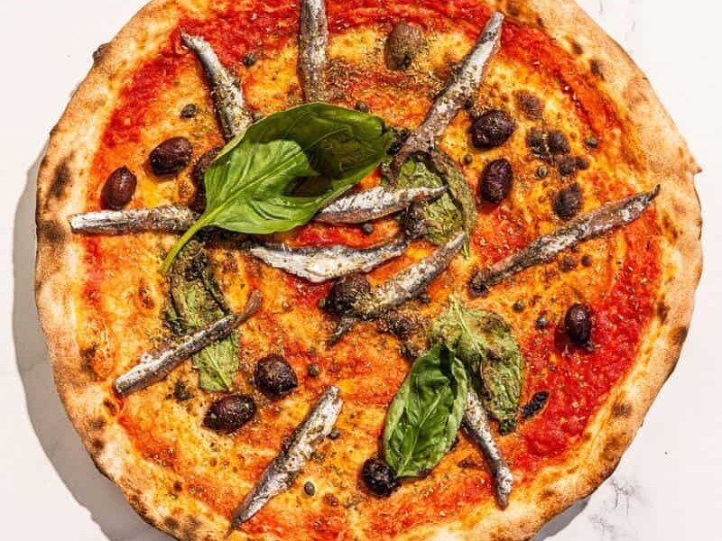 Traditional Napoletana pizza with San Marzano tomato, Cetara anchovies, Sicilian capers, Gaeta black olives, basil, and Coratina EVOO – no cheese