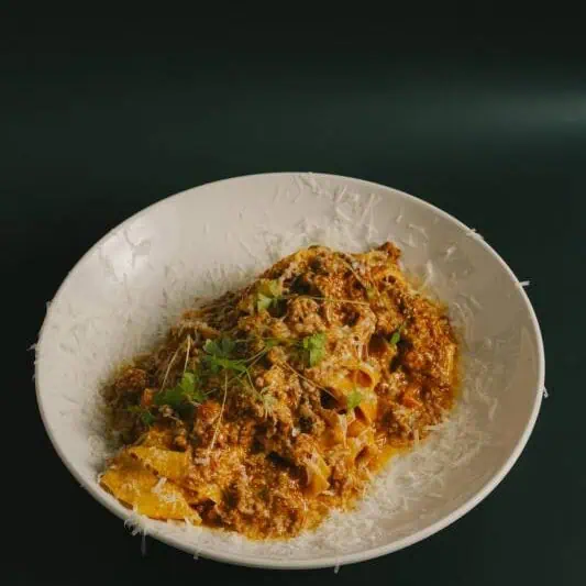 Wide pappardelle pasta tossed in a 5-hour slow-cooked pork and veal ragù with San Marzano tomatoes, Parmigiano Reggiano, and fresh basil