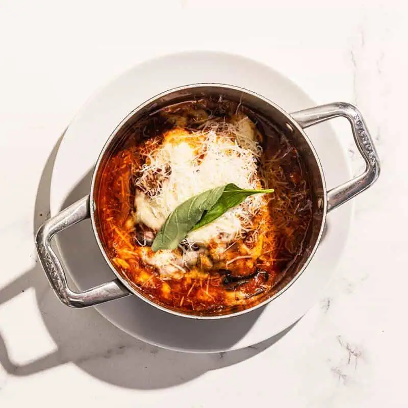 Baked eggplant parmigiana served in a skillet with melted scamorza cheese and Parmigiano Reggiano