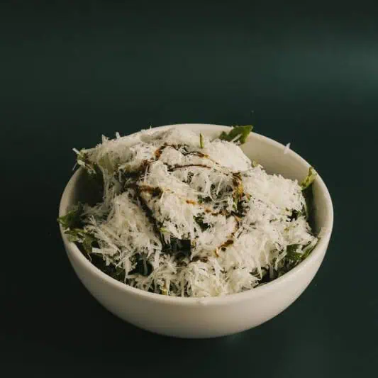 Fresh rucola (rocket) salad topped with grated Parmesan, drizzled with balsamic vinegar and extra virgin olive oil