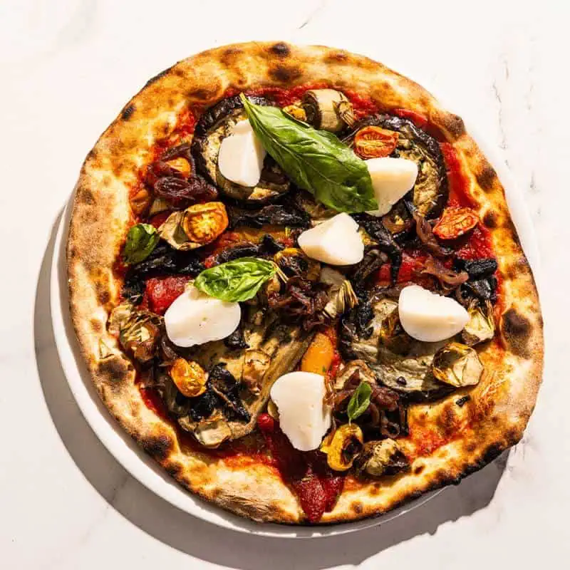Vegan Vegana pizza topped with San Marzano tomato, coconut cheese, grilled eggplant, roasted capsicum, sautéed mushrooms, marinated artichokes, basil, and Coratina EVOO